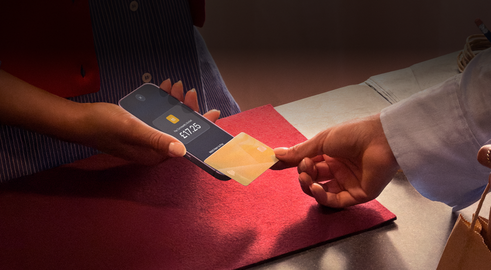 A hand taps a credit card to an iPhone to complete a transaction